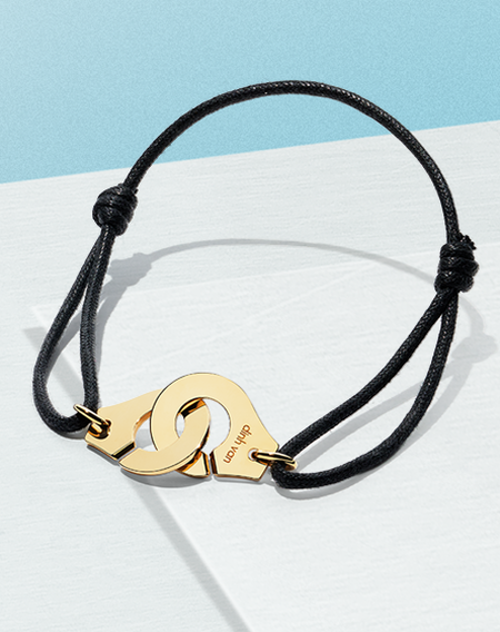 Menottes dihn van gold cold bracelet on a blue background.